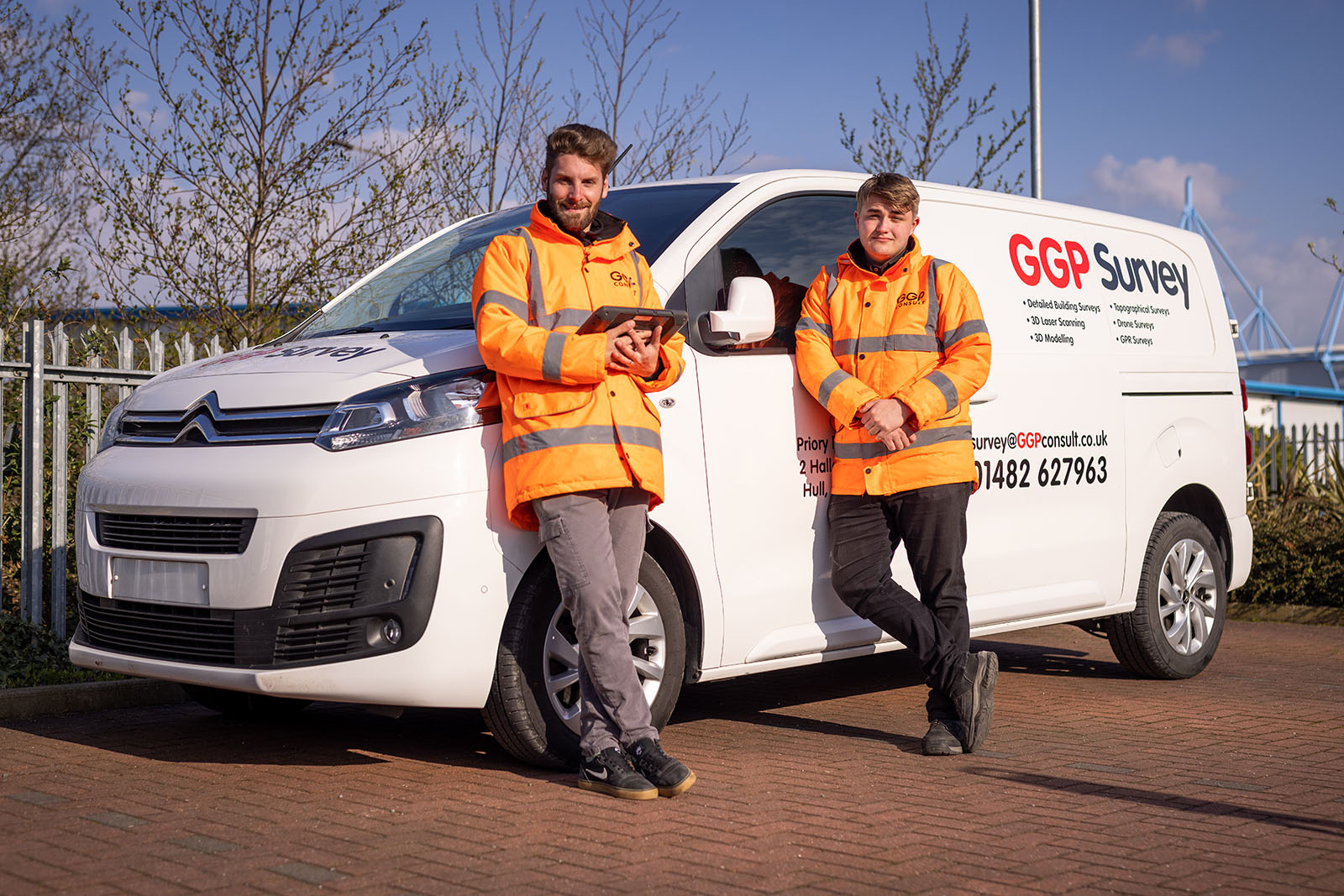 Two workmen in uniform stood in front of a GGP Survey van.